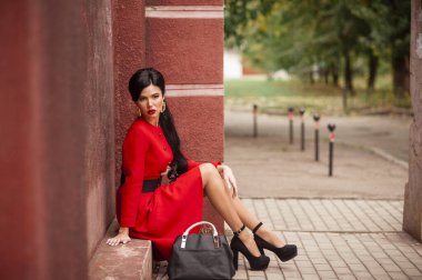 Kırmızı elbiseli ve kahve çantalı güzel bir kadın.
