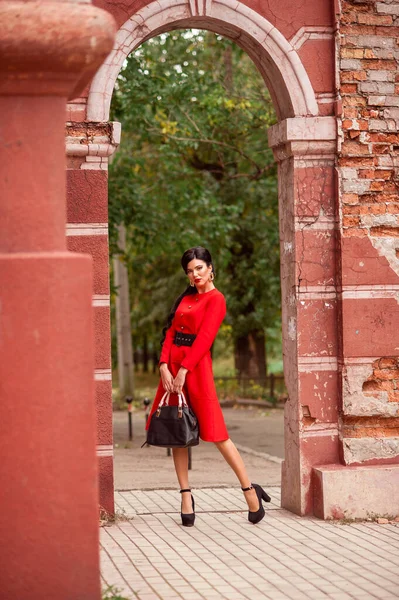 通りにポーズをとる赤いドレスの美しい若い女性 — ストック写真
