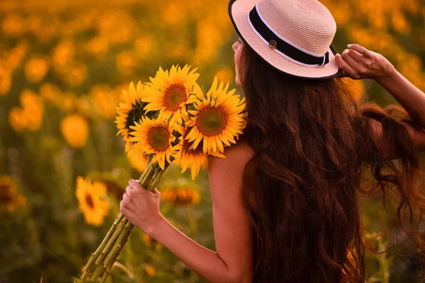 beautiful young woman with a bouquet of sunflowers in the field