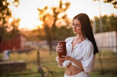 Genç ve güzel bir kadın parkta kahve içiyor.