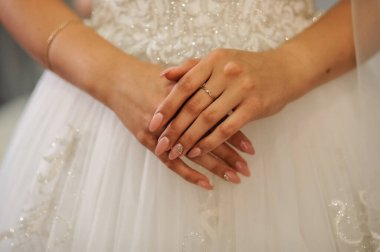 bride and groom holding hands on her wedding day with white and golden rings.