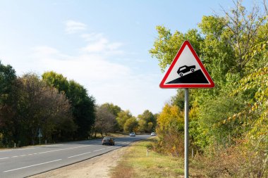 Chetrosu, Moldova - 17 Ekim 2021: Pist yakınlarındaki sonbahar ağaçlarının arka planına dik yol işareti