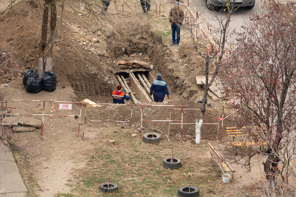 Тирасполь, Непризнанная Республика Приднестровье - 18 ноября 2021 года: Команда работников проводит ремонтные работы по тепловой сети в жилом районе города.