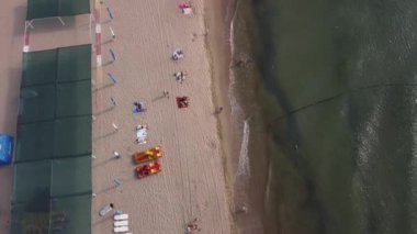 Sahil şeridi manzaralı. Tanımlanamayan insanlar Eylül ayında deniz kıyısında dinlenirken, güzel deniz dalgaları sahili yıkıyor. Karadeniz kıyısının orijinal videosu, Ukrayna, 4k, 25 fps