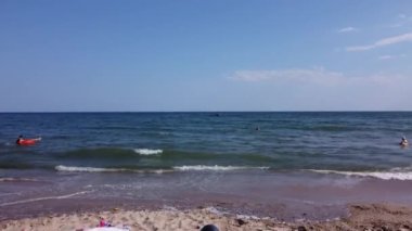 Eylül ayında öğleden sonra Karadeniz 'de insanlar plajda yüzer. Deniz dalgaları ve kum. Orijinal 4K video. Sahilden drone görüntüsü.