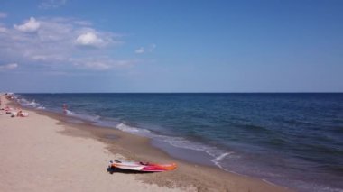 İnsanlar plajda yüzüyor. Plaj insanları güneşleniyor, güneşleniyor, deniz kenarında dinleniyor. Deniz dalgaları ve kum. Orijinal video 4k, 29.97 fps.