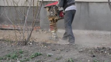 İşçi, evdeki kör bir alan için inşaat için taşınabilir titreşim rampası kullanıyor.