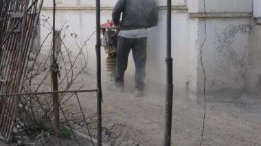 İşçi, evdeki kör bir alan için inşaat için taşınabilir titreşim rampası kullanıyor.