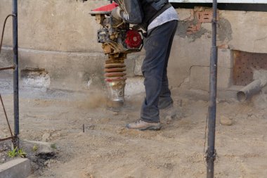 İşçi, evdeki kör bir alan için inşaat için taşınabilir titreşim rampası kullanıyor.