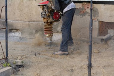 İşçi, evdeki kör bir alan için inşaat için taşınabilir titreşim rampası kullanıyor.