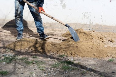 Temelde kör alan hazırlanıyor. Bilinmeyen bir Avrupalı işçi evin kör bölgesinin resmi işleri için kum döküyor. Temel formalite işaretlemesi. Evin yakınındaki kör alan inşaatı