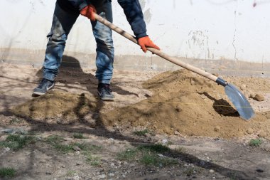 Temelde kör alan hazırlanıyor. Bilinmeyen bir Avrupalı işçi evin kör bölgesinin resmi işleri için kum döküyor. Temel formalite işaretlemesi. Evin yakınındaki kör alan inşaatı