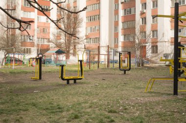 Apartman binalarının avlusunda açık spor salonu. Halka açık alanda spor aletleri. Parkta spor simülatörleri