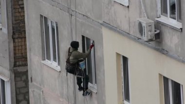 Tiraspol, Moldova - November 19, 2021 High-rise works. View of a worker climbing a wall of an apartment building to finish window slopes