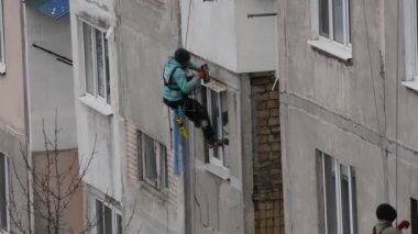 Tiraspol, Moldova - 19 Kasım 2021 Yüksek Binalar. Pencere yamaçlarını tamamlamak için bir apartmanın duvarına tırmanan bir işçinin görüntüsü