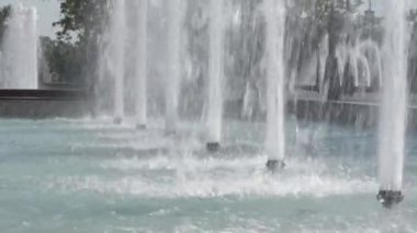 Şehir parkındaki çeşmeden su akar. Çeşme sıçraması. Su basıncı. Yaz parkında yüksek çeşme. Fıskiyeler fışkırıyor.
