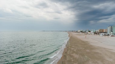 Evening beach in Romania. Drone view of Mamaia beach in Romania. Beach umbrellas, Black Sea waves, golden sand, lifeguard tower in the resort area of Europe, Romania, Constanta in September. clipart