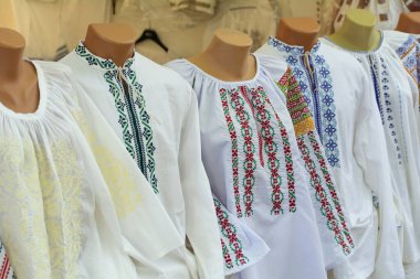 Moldova nakışı. Fuarda erkek ve kadın Moldovalı işlenmiş gömlekler. Balkan ulusal geleneksel kostüm giysileri nakışladı