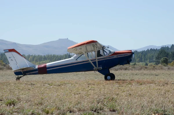畑の未舗装の滑走路に小さな飛行機を離陸するタクシー ホワイトブルーとレッドプロペラ軽飛行機 — ストック写真