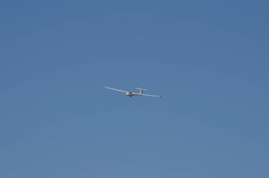 Arka planda mavi bir gökyüzü ile havada süzülen planör. Çok hafif planör uçuşu