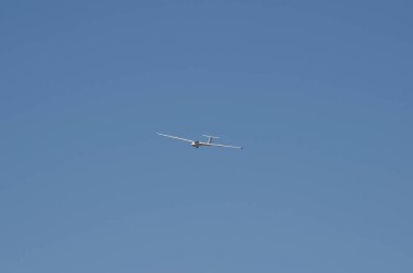 Yüksekten uçan planör, ön planda mavi gökyüzü ile görünüyor.