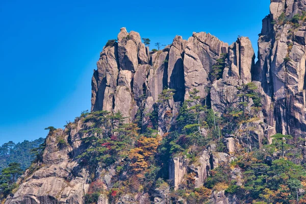 Yeşil ağaçlı yüksek granit dağlar, mavi gökyüzü ve beyaz bulutlar. Huangshan Dağı manzarası (Sarı Dağ). UNESCO Dünya Mirası Alanı. Anhui Eyaleti, Çin.