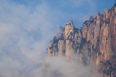 Granit dağı çevreleyen beyaz bulutların dinamik görüntüsü. Huangshan Dağı manzarası (Sarı Dağ). UNESCO Dünya Mirası Alanı. Anhui Eyaleti, Çin.