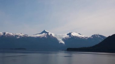 Yeşil ağaçlı dağ. Arka planda karlı bir dağ var. Alaska fiyortları, eşsiz doğal manzaralar. Alaska, ABD. Haziran 2019.