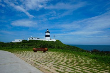 Mavi gökyüzü ve beyaz bulutların altında Fugui Cape Deniz Feneri. Siyah beyaz duvar. Tayvan 'ın en kuzeydeki deniz feneri Fugui Burnu, Shimen Bölgesi, New Taipei Şehri' nde yer almaktadır..