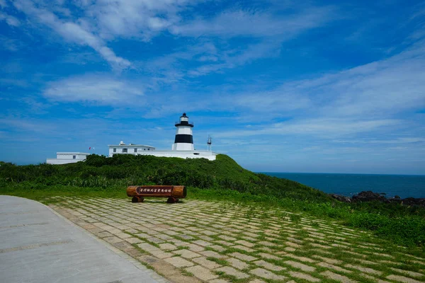 Mavi gökyüzü ve beyaz bulutların altında Fugui Cape Deniz Feneri. Siyah beyaz duvar. Tayvan 'ın en kuzeydeki deniz feneri Fugui Burnu, Shimen Bölgesi, New Taipei Şehri' nde yer almaktadır..