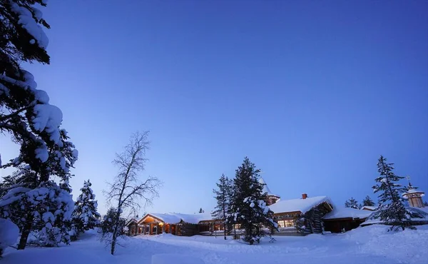 Mavi yıldızlı gökyüzünün altındaki Noel Baba Köyü. Karla kaplı bir kış. Rovaniemi 'deki Noel Baba Köyü, Laponya, Finlandiya.