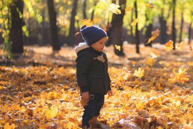 Sonbahar yapraklarında oynayan çocuk