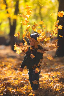 Sonbahar yapraklarında oynayan çocuk