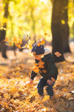Sonbahar yapraklarında oynayan çocuk