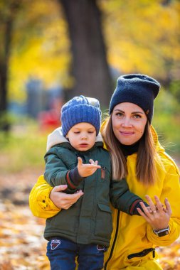 Sonbahar yapraklı çocuk annesiyle uğur böceğine bakıyor.
