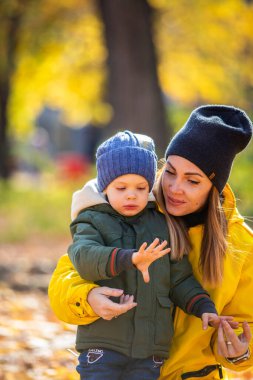 Sonbahar yapraklı çocuk annesiyle uğur böceğine bakıyor.
