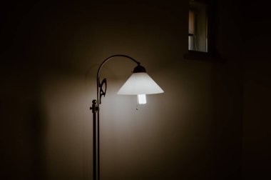 Karanlık bir odada duran eski bir lamba.