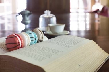 İçinde makaronlar olan klasik bir kitap. Kahverengi, kırmızı ve beyaz. Arka planda klasik çay fincanı