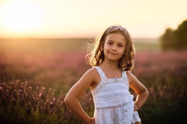 Beyaz İspanyol kız gün batımında lavantanın arasında oynuyor.