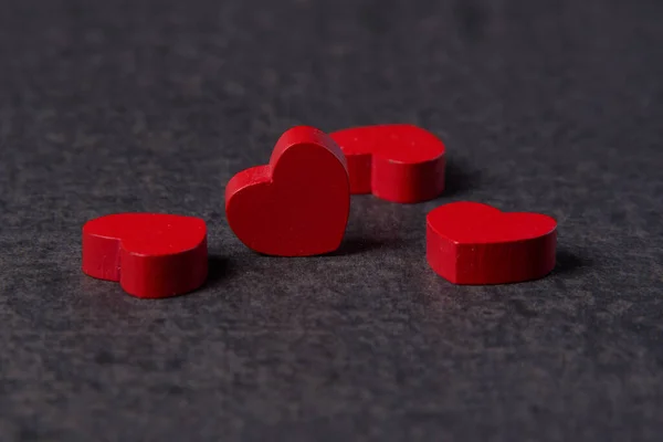 Cuatro corazones de madera roja sobre una mesa gris — Foto de Stock