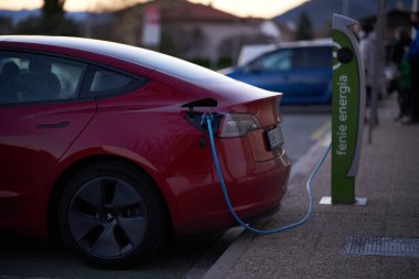 Şarj istasyonuna bağlı modern kırmızı elektrikli araç.