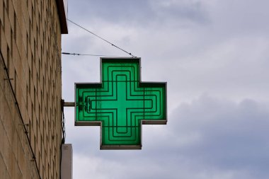 Arka planda gökyüzü olan yeşil haç şeklinde eczane işareti