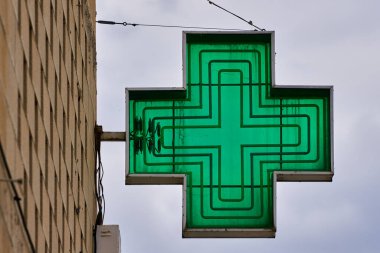 Arka planda gökyüzü olan yeşil haç şeklinde eczane işareti