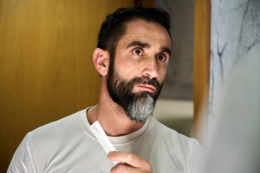 Genç adam aynanın önünde tarağıyla sakalını tarıyor. Yüksek kalite fotoğraf