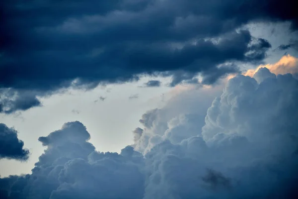 Dramatic sky with dark clouds and a small light illuminating a white cloud. High quality photo