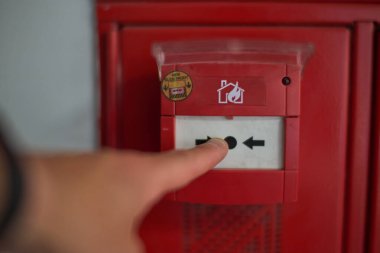 Hand pressing on the trigger of a fire alarm. High quality photo