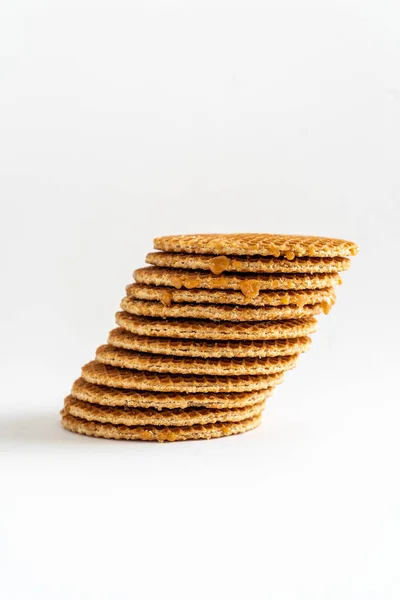 A stack of Dutch syrup waffles (translation: stroopwafels) leaning at an angle on white background
