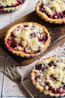 Three home baked plum crumble tarts on cutting board