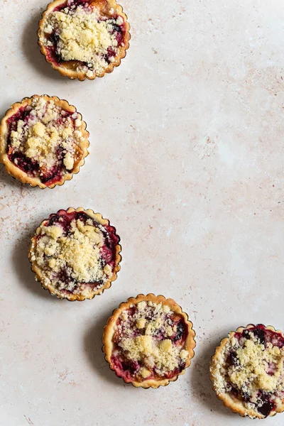 Five home baked plum crumble tarts in diagonal round shape from above