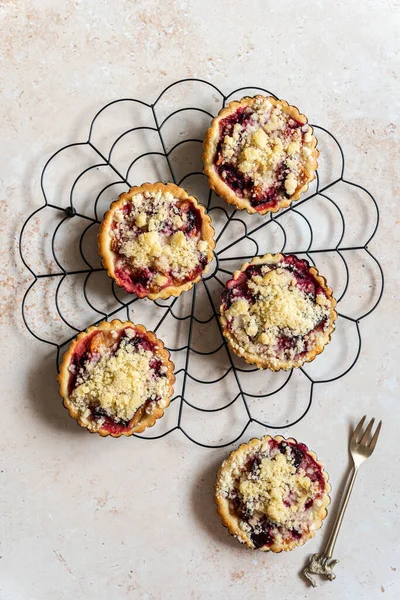 Several home baked plum crumble tarts on cooling rack from above